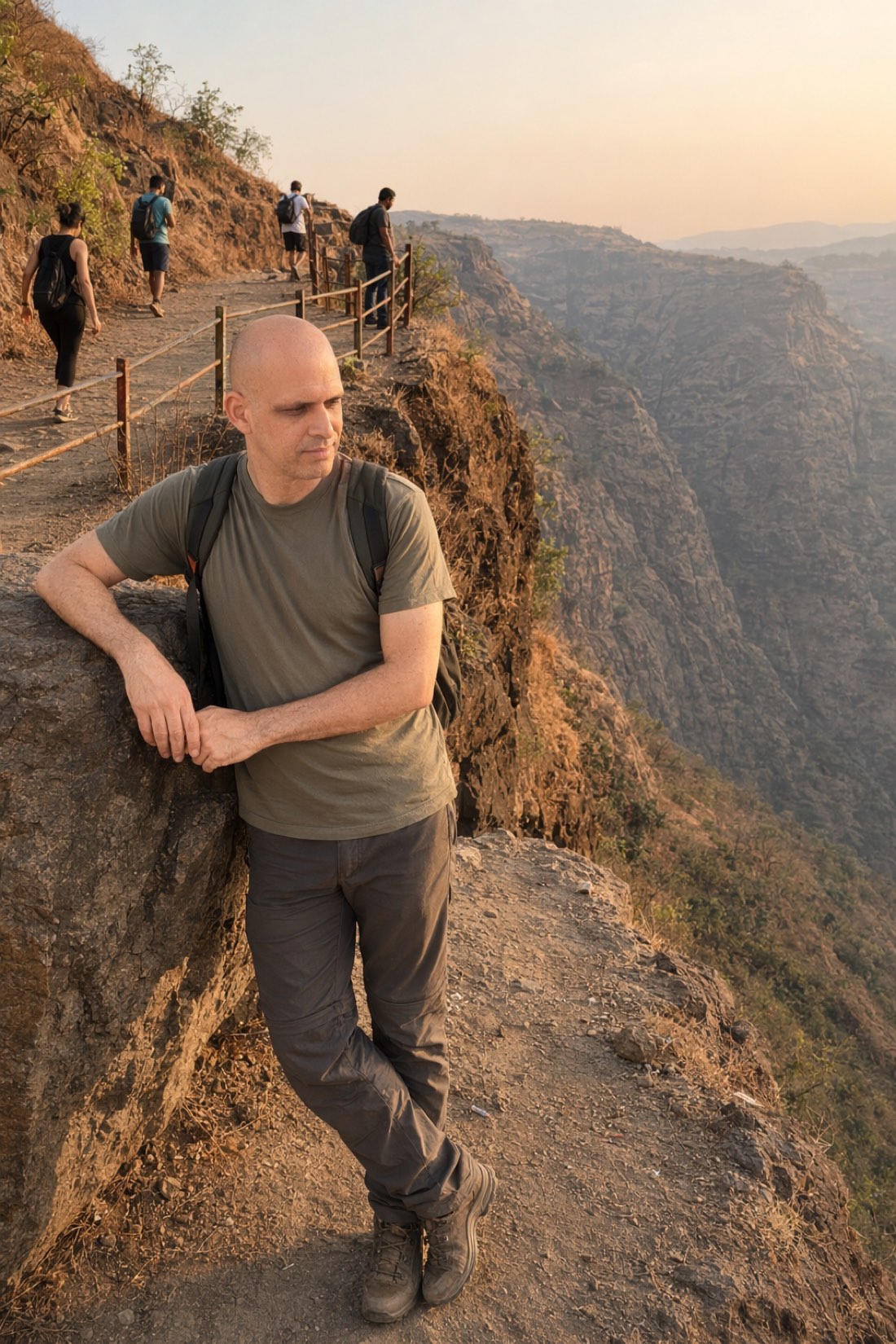 Fearful-avoidant in one image: standing at the edge of the thing it wants. Man leaning on a cliff-edge rock at sunset, looking away from the trail
