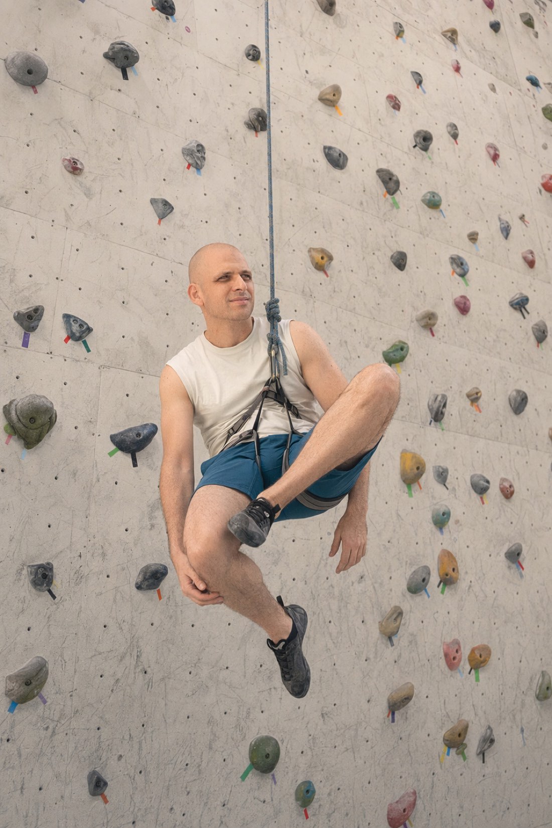 The bench, pictured. Comfortable, technically at the gym, going nowhere. Man resting in a climbing harness, hanging off the wall