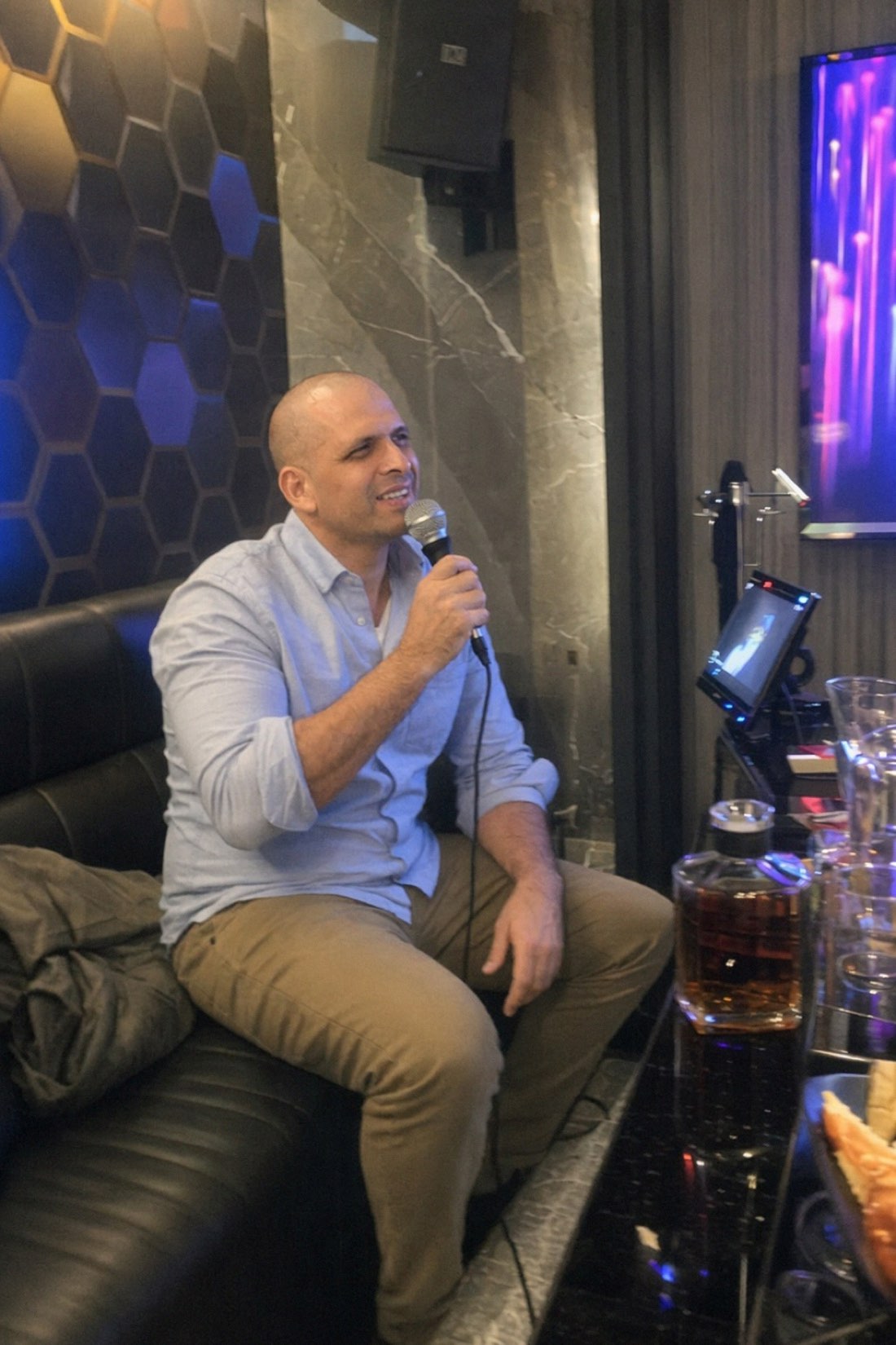 Man mid-song at karaoke night, warm to the whole room and asking nothing back for it