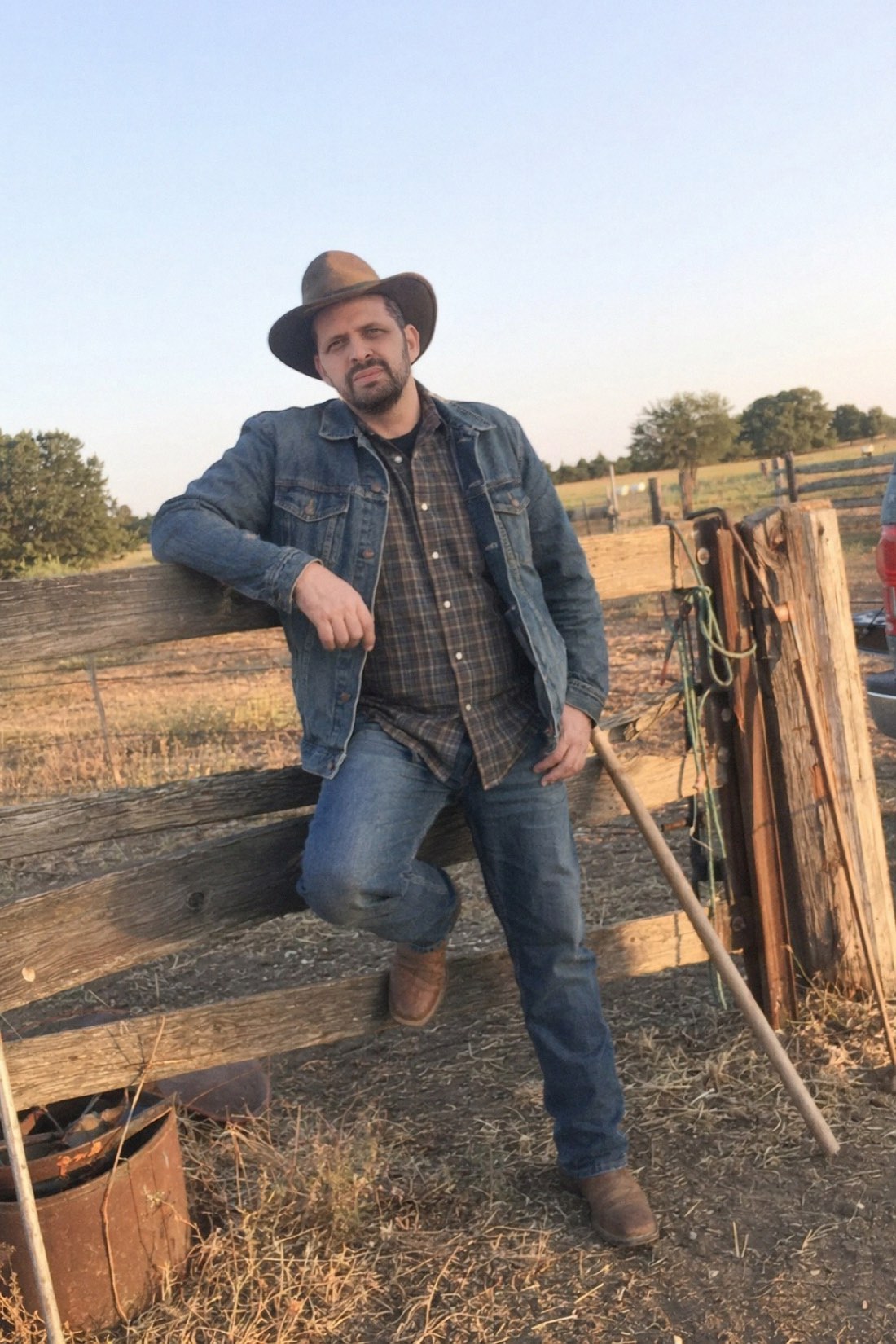 Man in denim leaning on a fence at sunset, a characterful AI dating profile photo