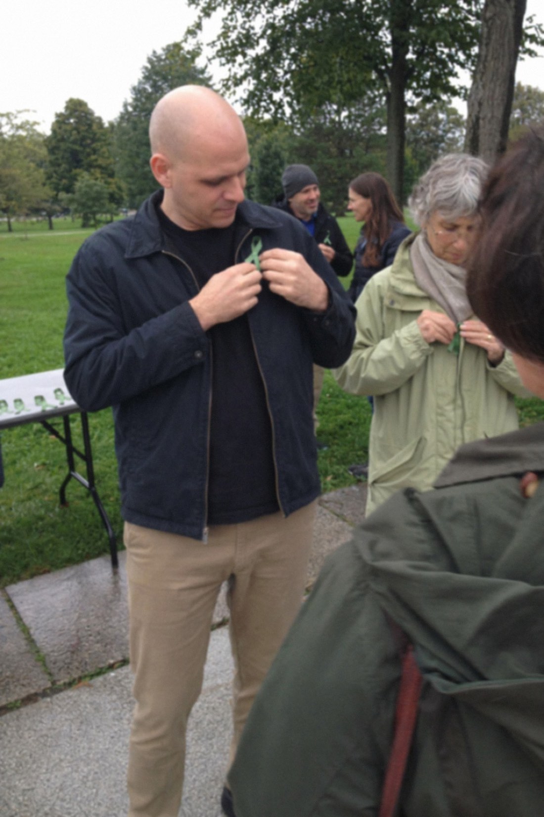 Man pinning a green awareness ribbon at a park gathering