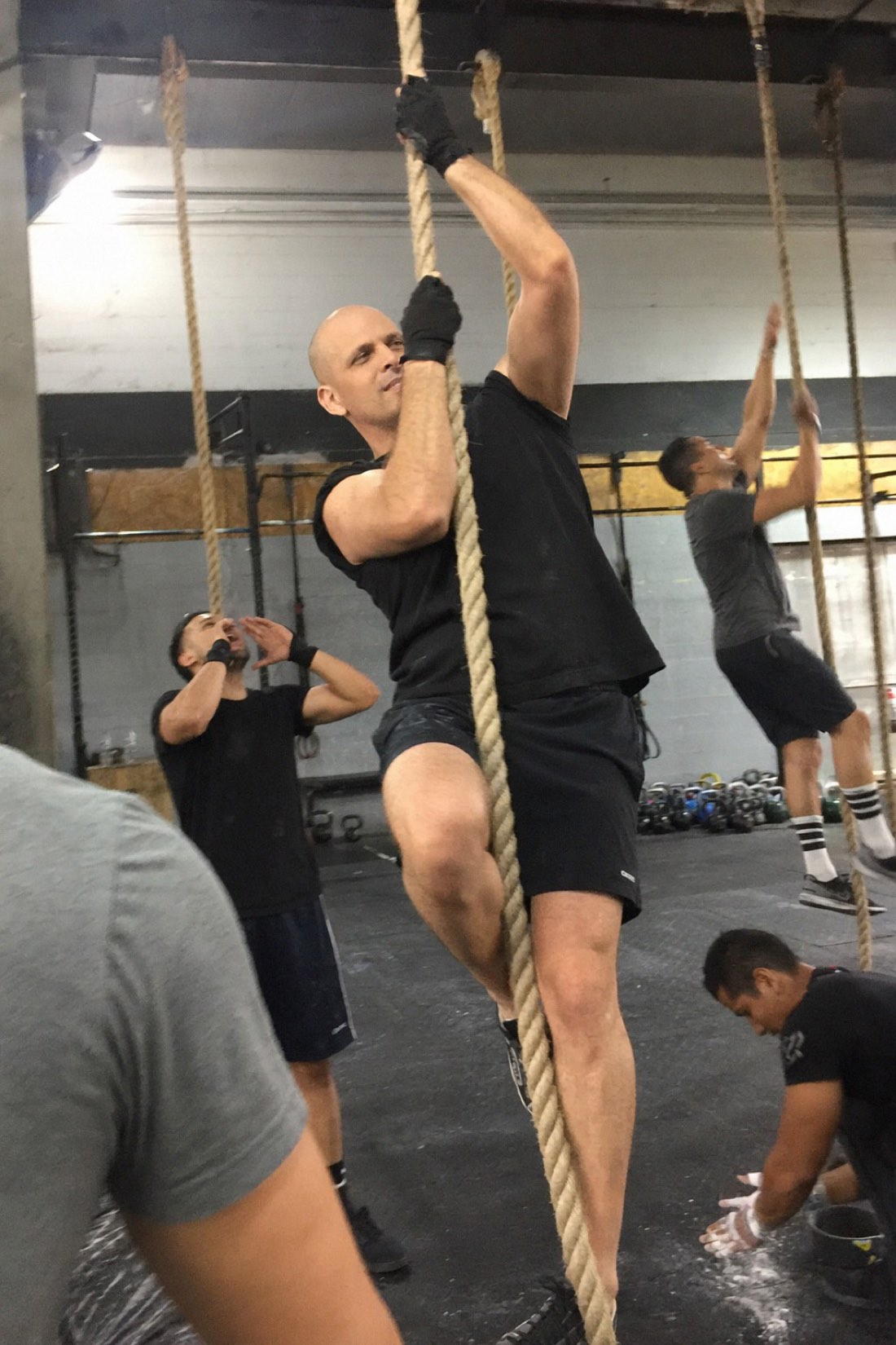 Man climbing a rope at a gym with a steady grip, the secure attachment posture in one image