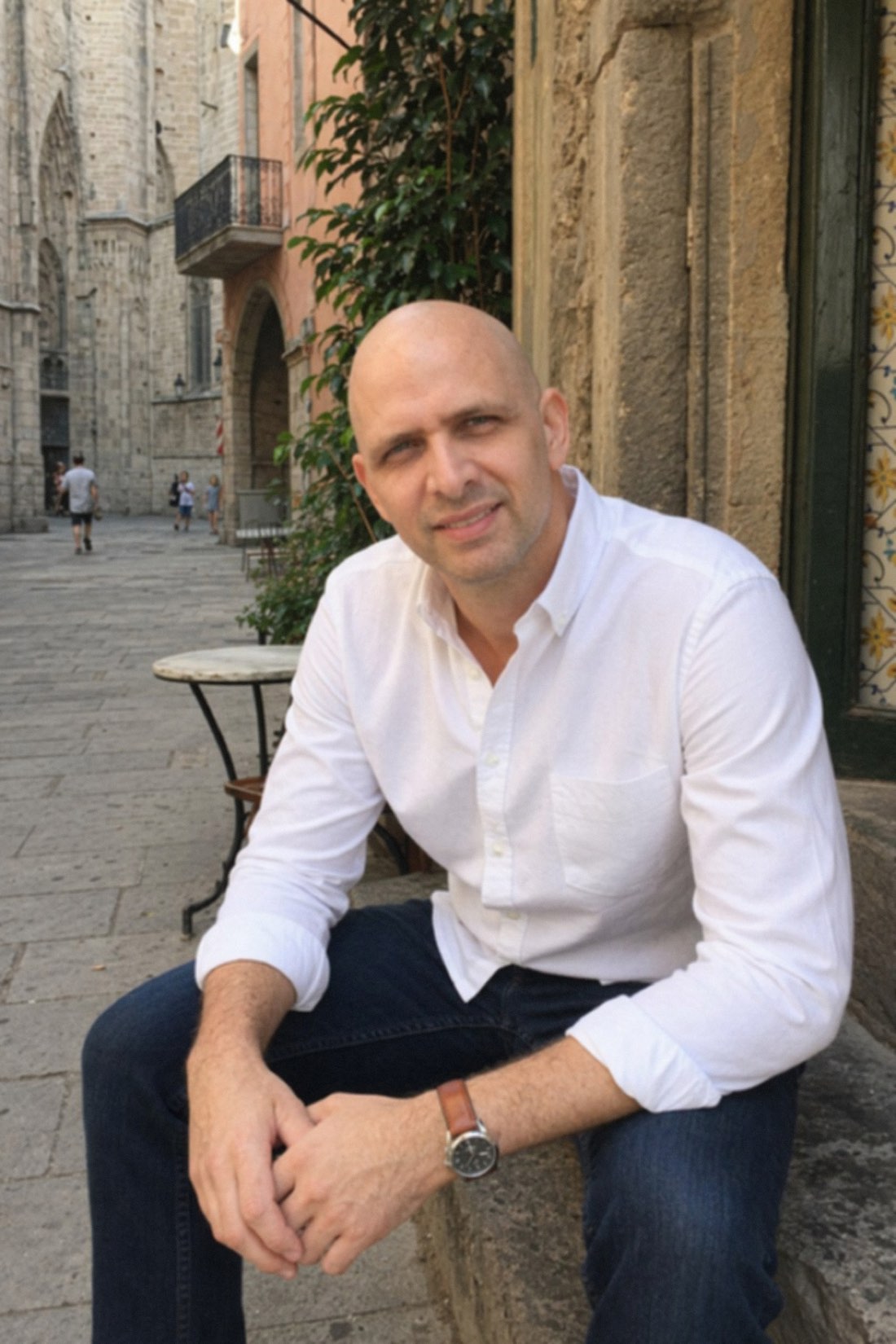 Man sitting on a sunny old-town street by a café, a clean everyday AI photo