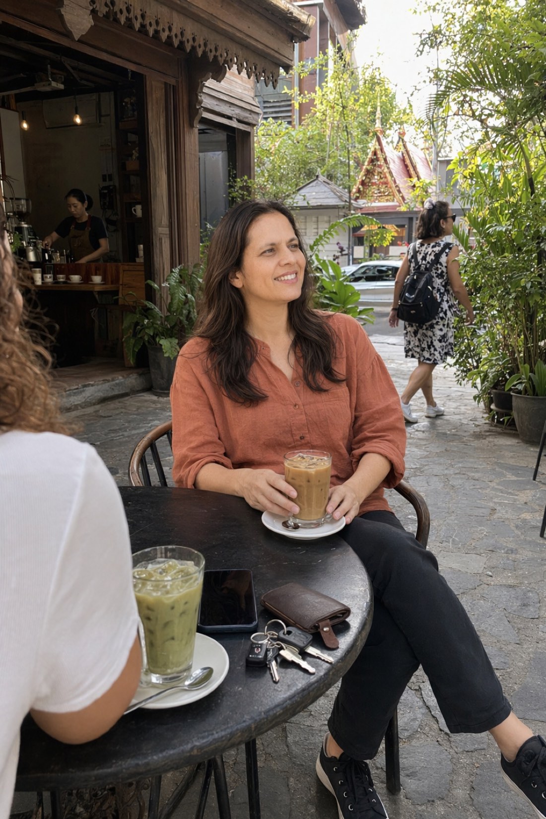 Woman having iced coffee at a wooden café on a tropical street