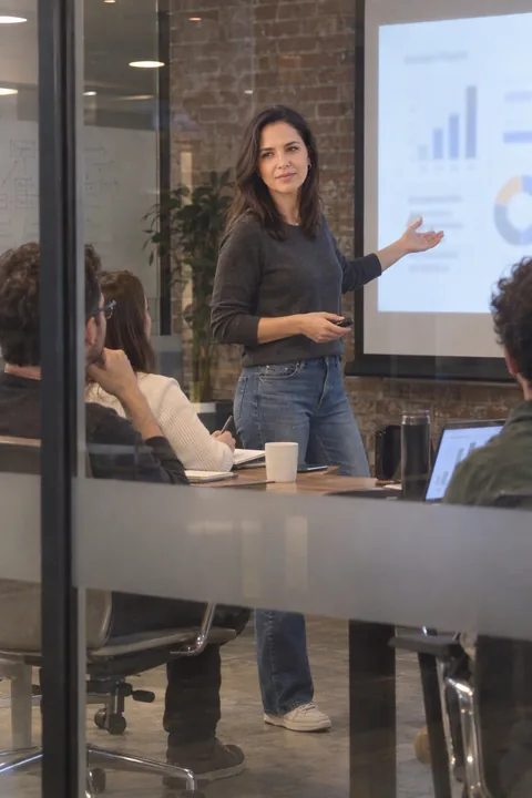 AI LinkedIn photo example: presenting in a brick-walled startup room, seen through the glass